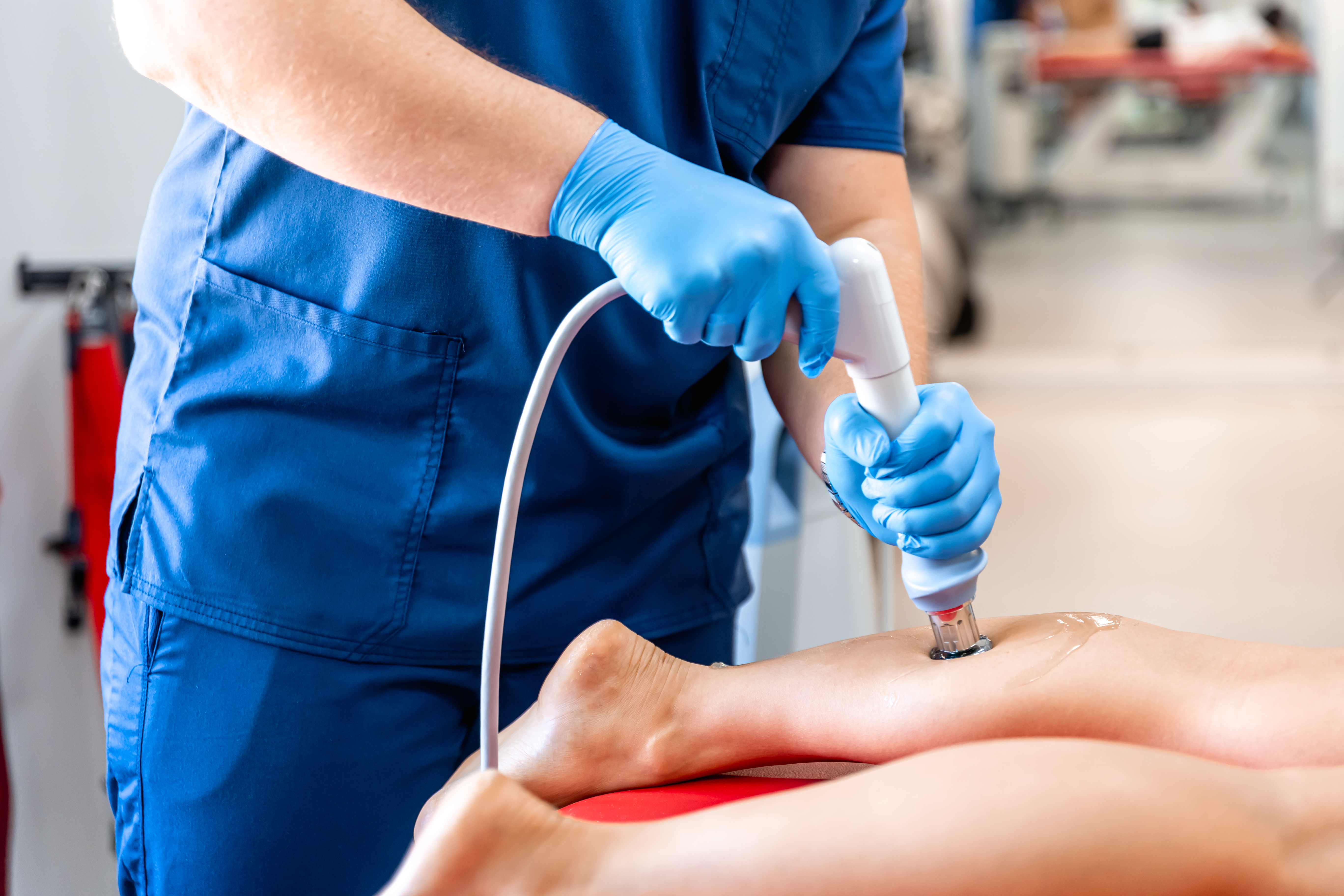 Shock wave therapy, the magnetic field, rehabilitation, physiotherapist doctor performs surgery on a patient's shin.